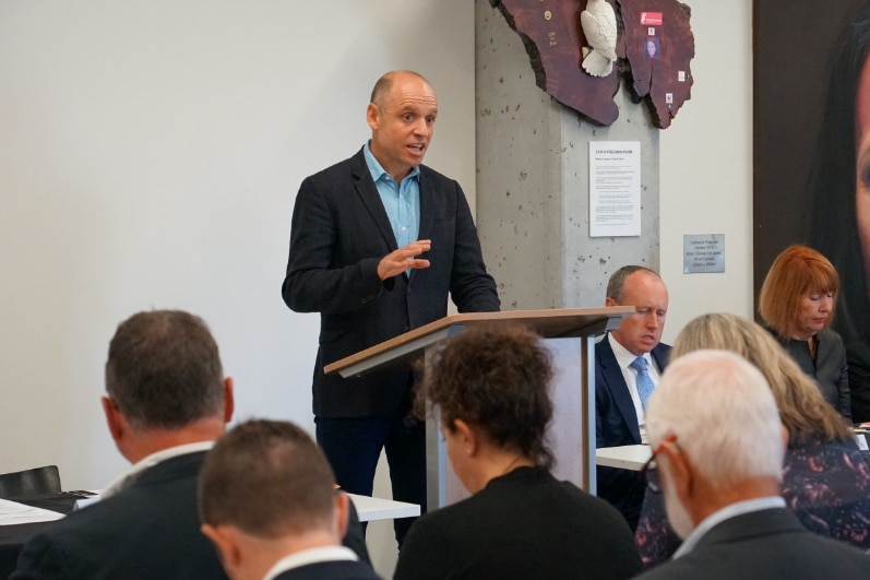 A man at a podium speaks to a crowd