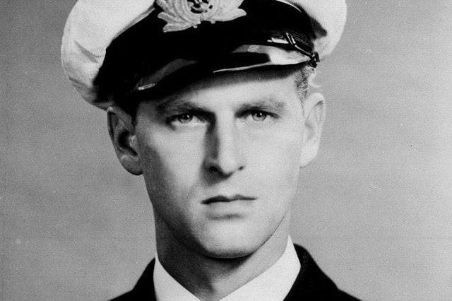 A black and white photograph of a young Prince Philip posing for a portrait in the navy.
