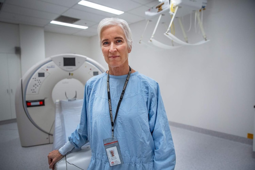 A blonde haired woman in scrubs in a operating theatre.