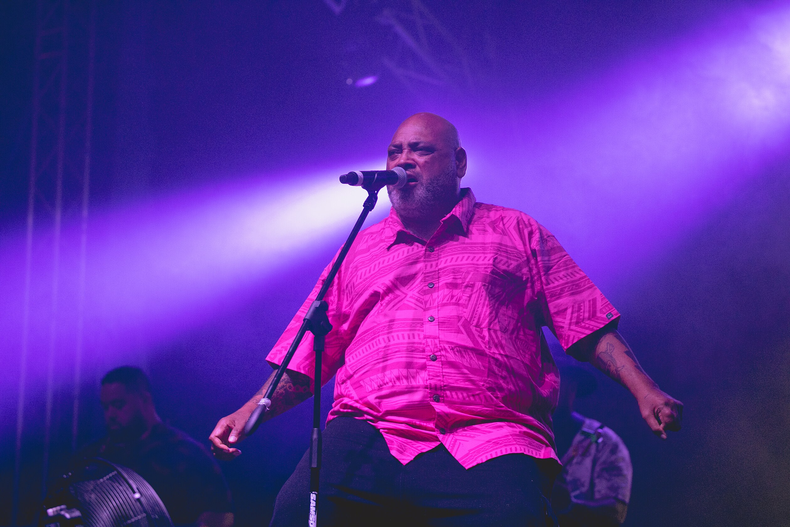 Fiji sits in front of a microphone singing. 