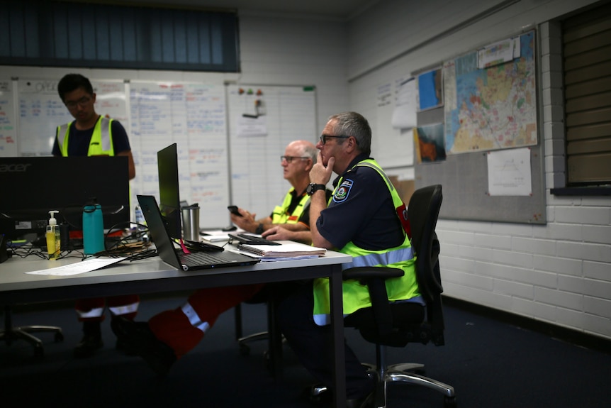 Three men in hi-vis vests at work inside a Department of Fire and Emergency Services command centre in Broome.