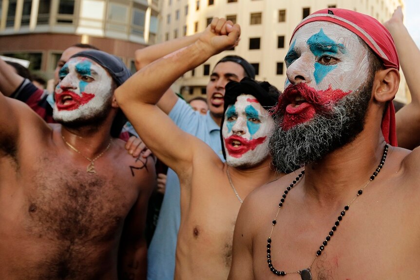 Male protester face-painted without shirts in the streets.