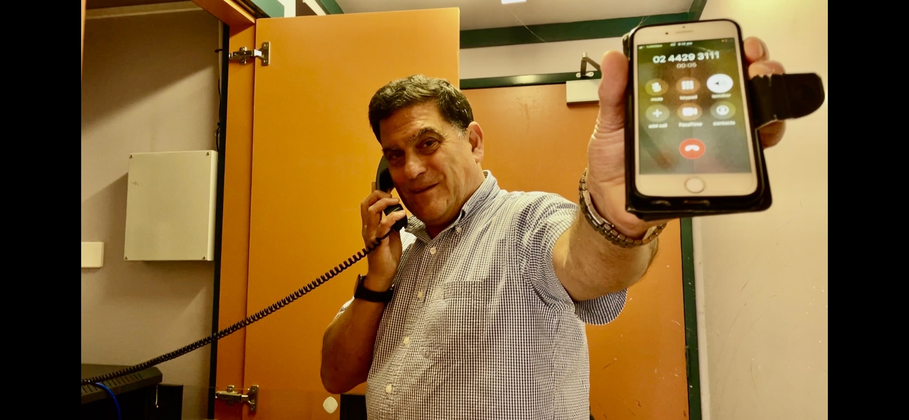A man demonstrating how a satellite phone works from landline to mobile.