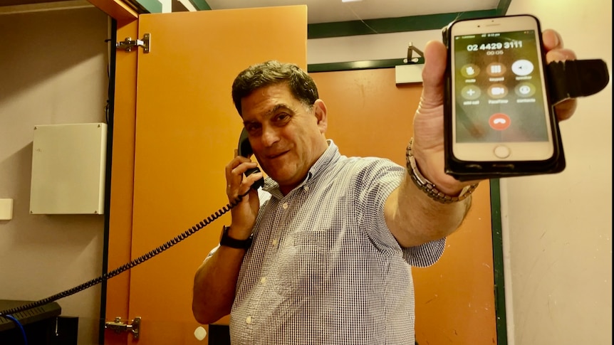 一位男士演示了卫星电话如何从固定电话连接到移动电话。