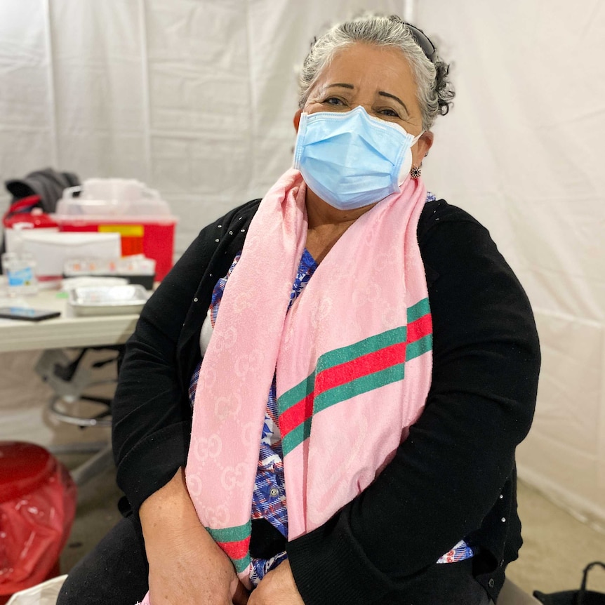 A woman in a face mask sits on a chair