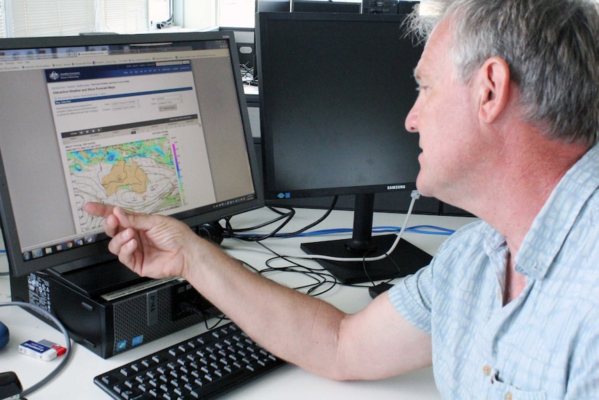 Man points to a computer model illustrating weather patterns.