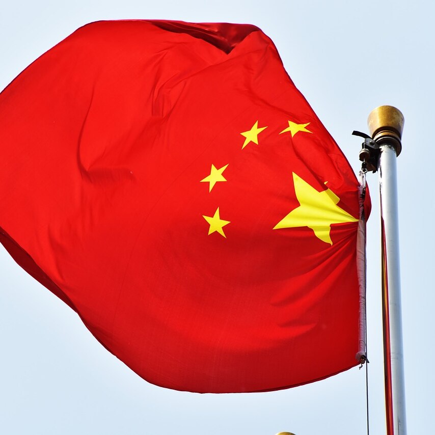 A Chinese flag blows in the wind off a flag pole