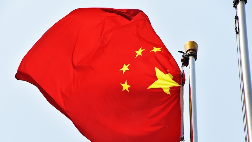 A Chinese flag blows in the wind off a flag pole