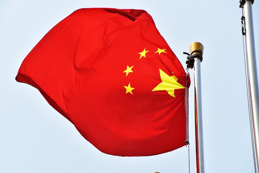 A Chinese flag blows in the wind off a flag pole