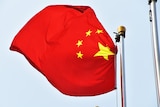 A Chinese flag blows in the wind off a flag pole