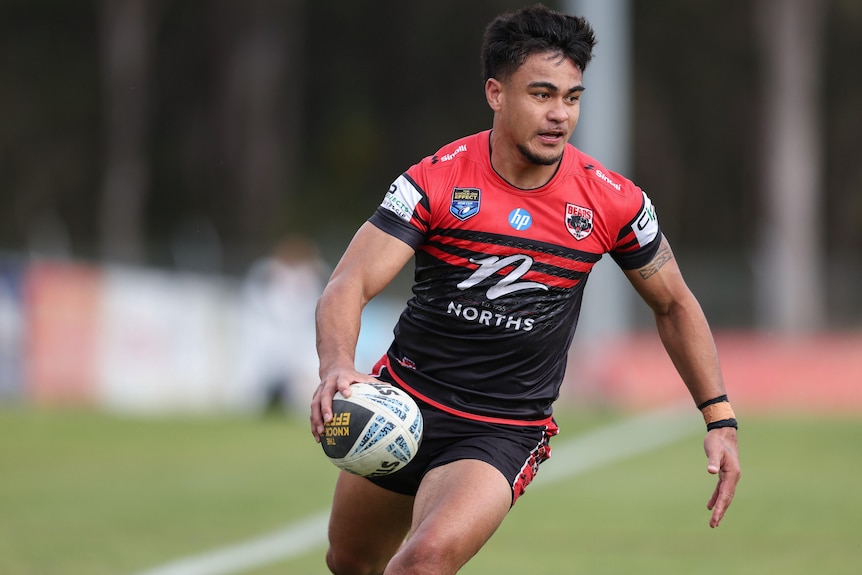 A man runs the ball during a rugby league match