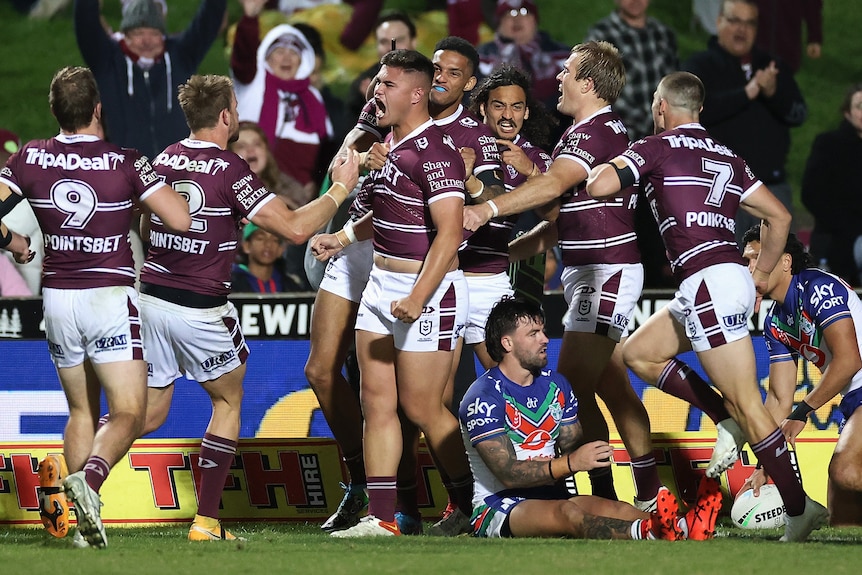 A group of Manly players celebrate together