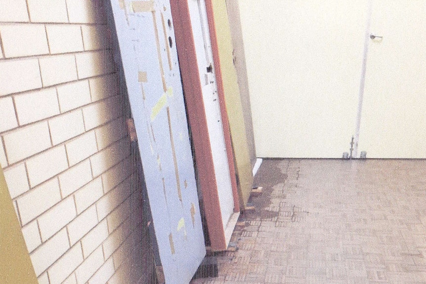 Water pooling under Yuendumu Doors stored in corridor.