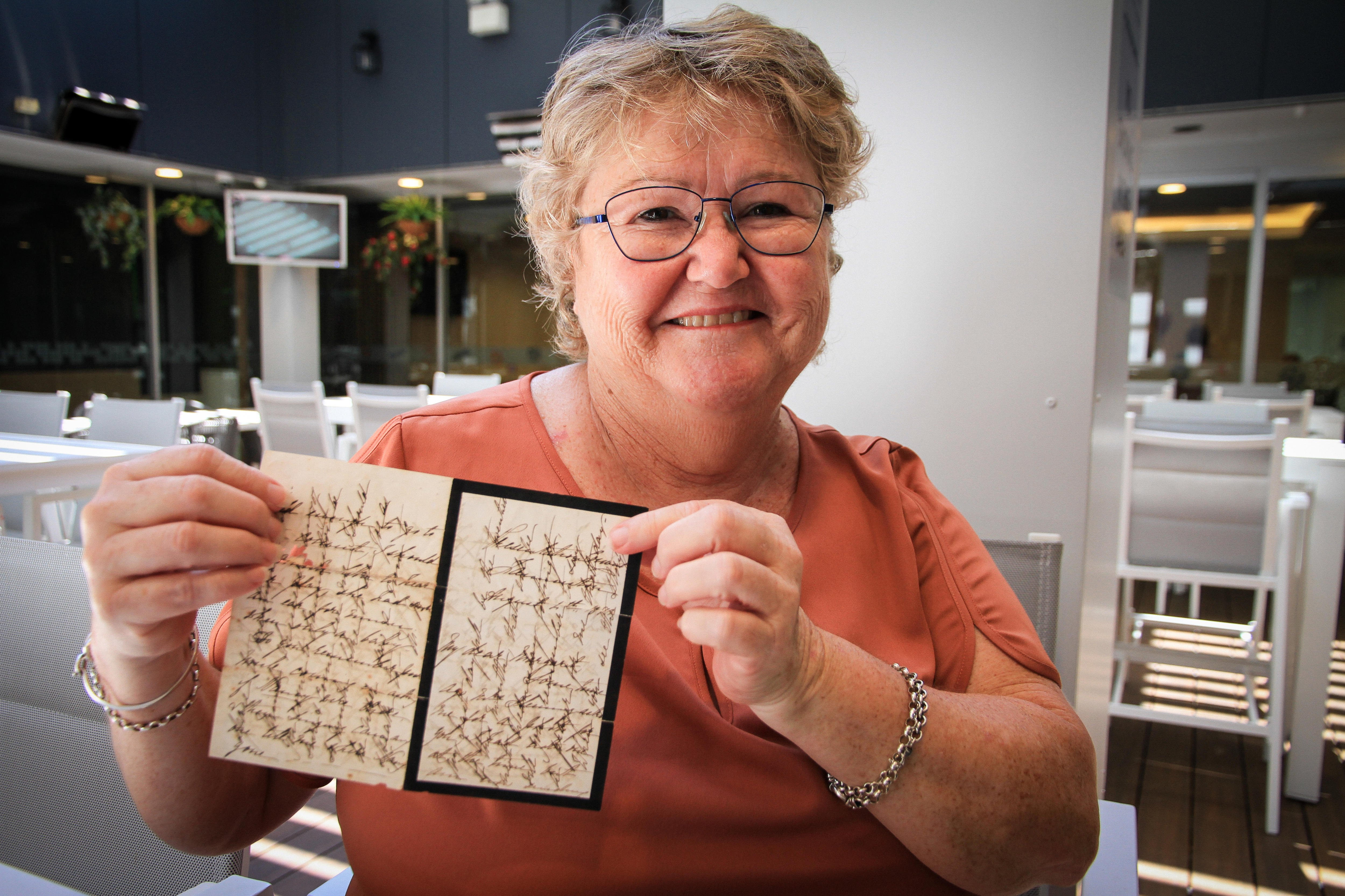 A woman sits in a club holding a criss-crossed letter