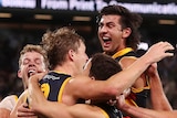 Adelaide Crows players jump on and run to hug Jordan Dawson after a winning goal against Port Adelaide.
