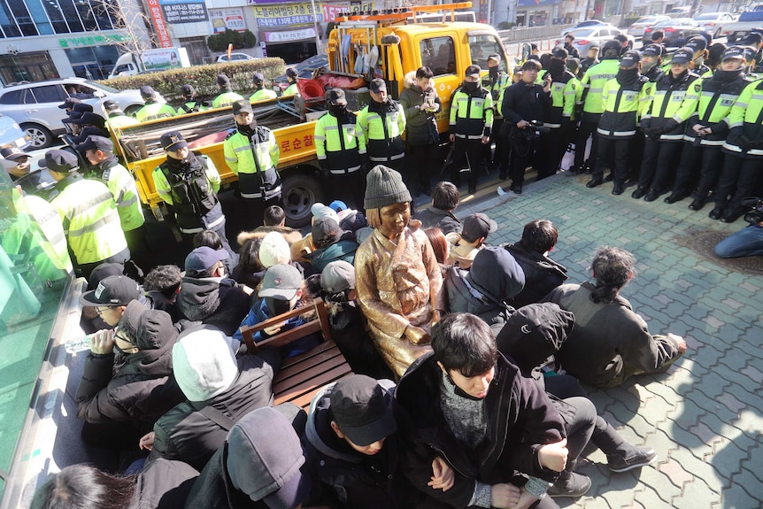 Members of civic groups sit around a comfort-woman statue after they set it up in front of the Japanese consulate in Busan, South Korea