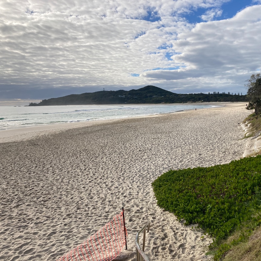 An empty beach with Cape Byron in the background.