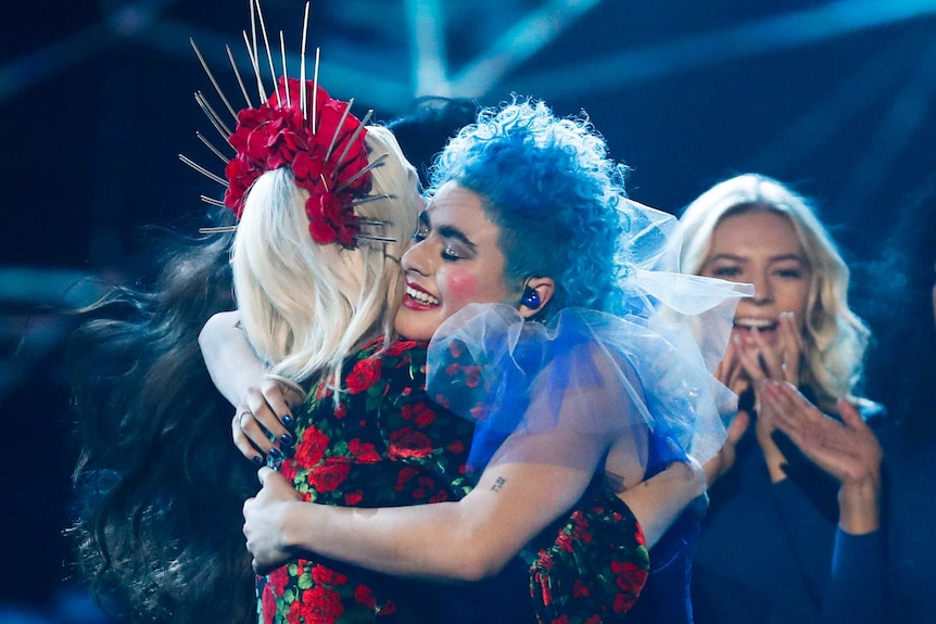 Kate Miller-Heidke, wearing a pointy red crown, hugs Montaigne, wearing a blue frilly collar, at Eurovision - Australia Decides.