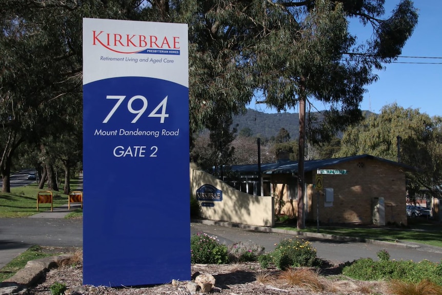 A large blue sign reading Kirkbrae with gum trees behind it.