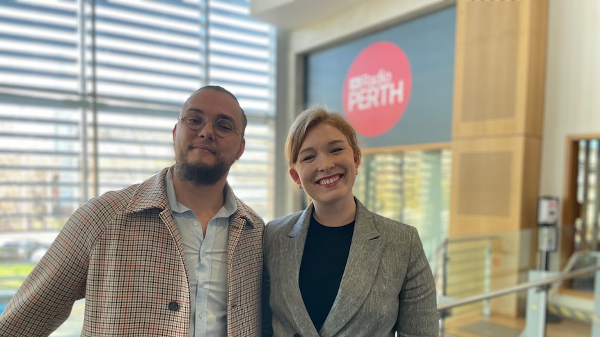 A young man and woman stand in the foyer of ABC Radio Perth, smiling at the camera