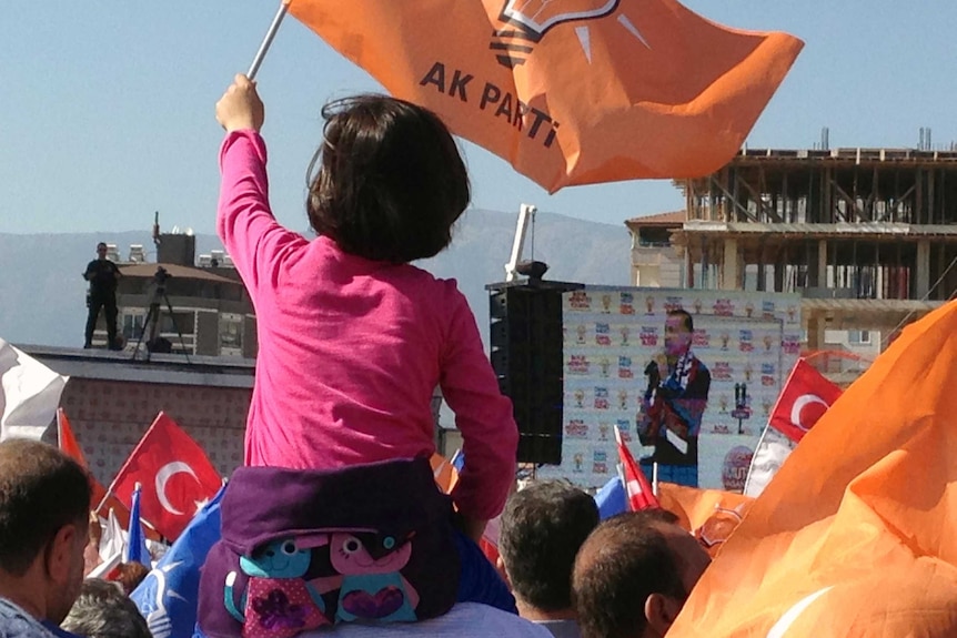 A young girl waves a flag as AKP supporters listen to a speech by Recep Tayyip Erdogan in Antakya.