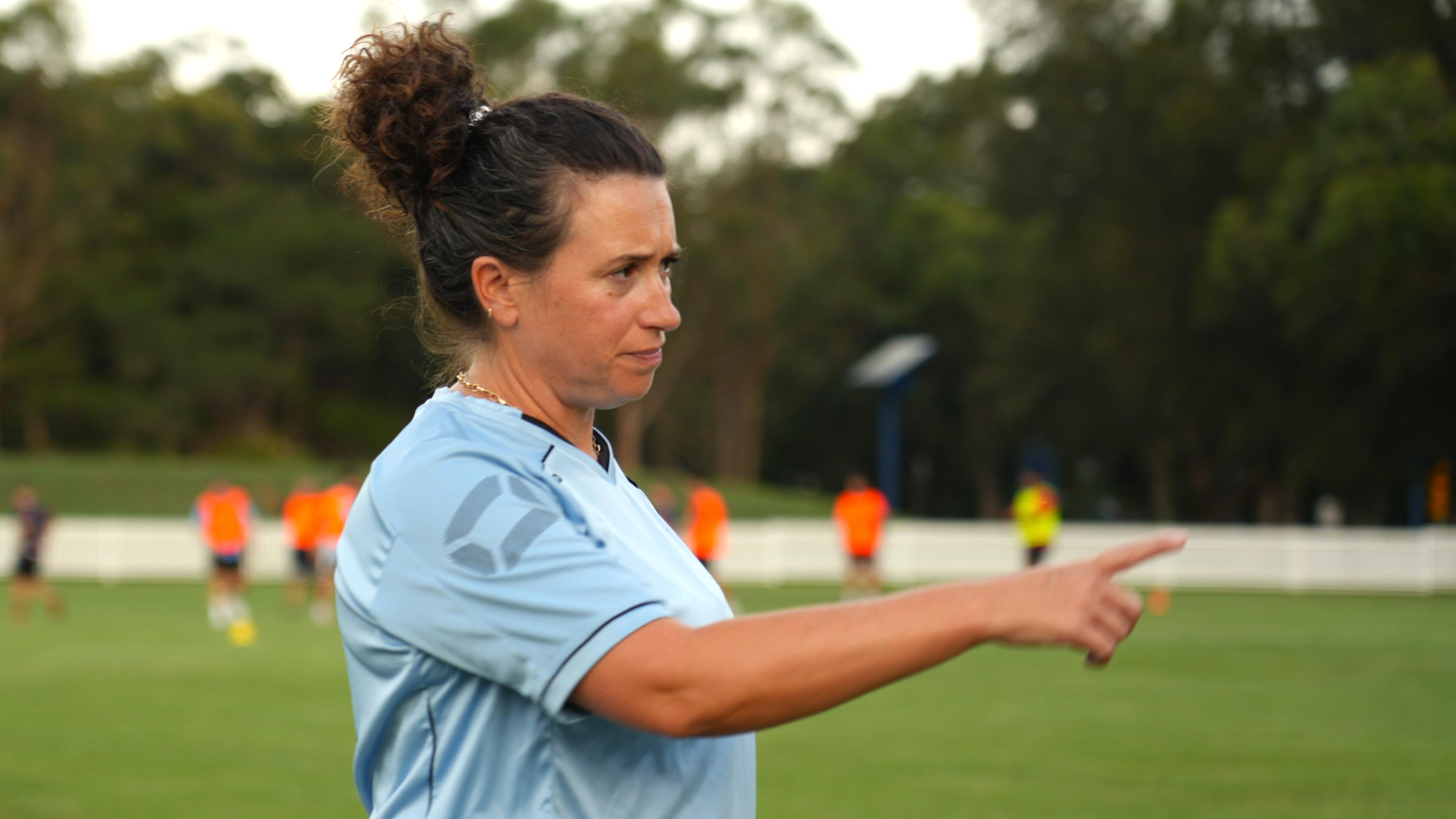 A female footballer in her 40s points during a training session
