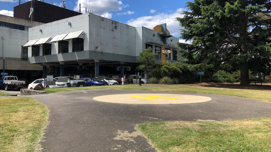 A helipad is seen next to a large building.