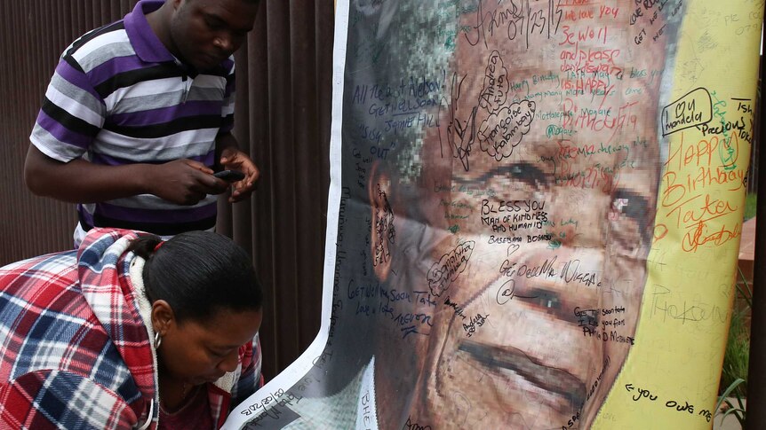 A woman adds a message on a poster of Nelson Mandela