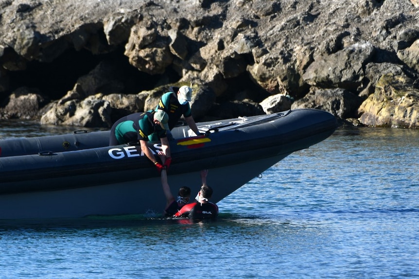 Spanish Civil guards pull a man into an inflatable boat after he arrived swimming to the Spanish enclave of Ceuta.