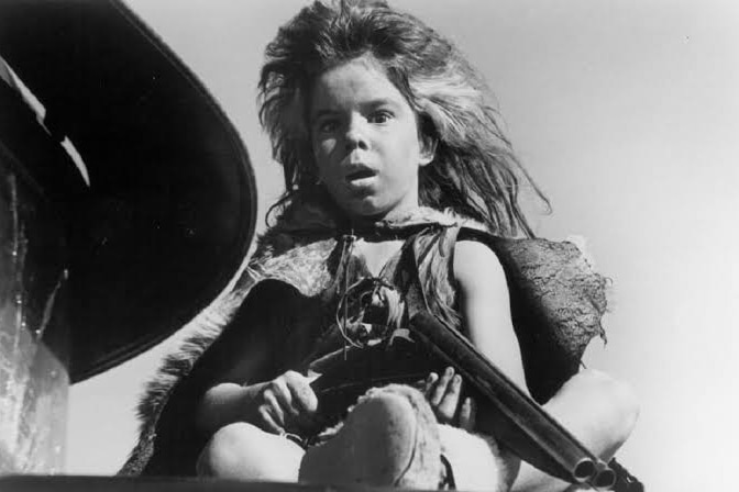 Black-and-white image of a young boy dressed as a feral in Mad Max.
