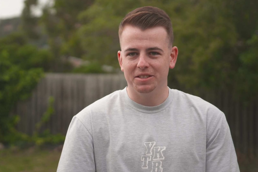 Young man in a grey shirt looking at the camera.