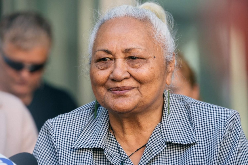 A close up of Anna with a slight smile or look of relief on her face outside a court house.