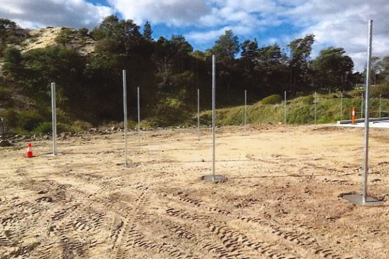 Fencing poles set in concrete at a construction site.