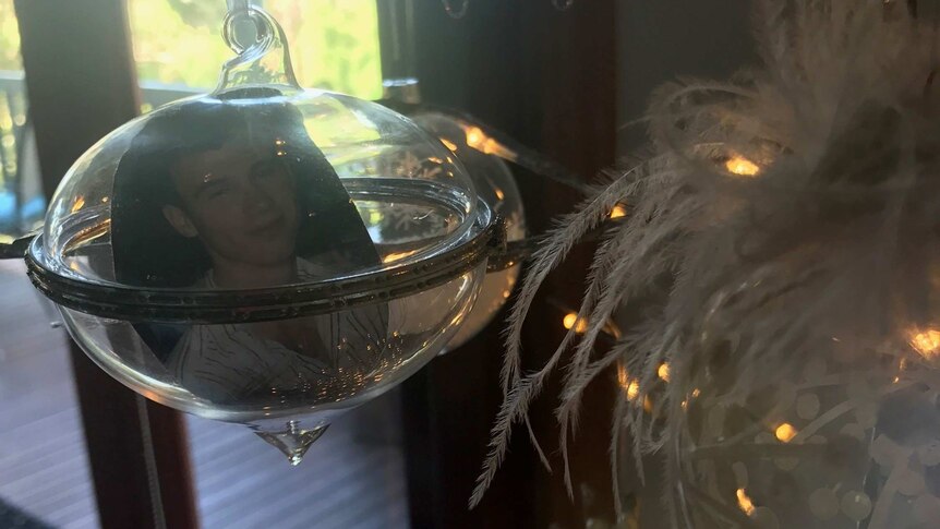 A glass christmas bauble with a cut out photo of Alex Eales inside.