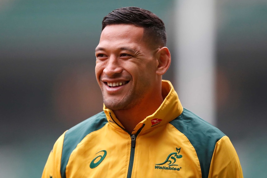 Israel Folau in a Wallabies jacket smiles at someone off camera