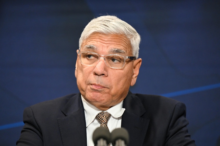 A close shot of Mundine's face, microphones just visible in the foreground.