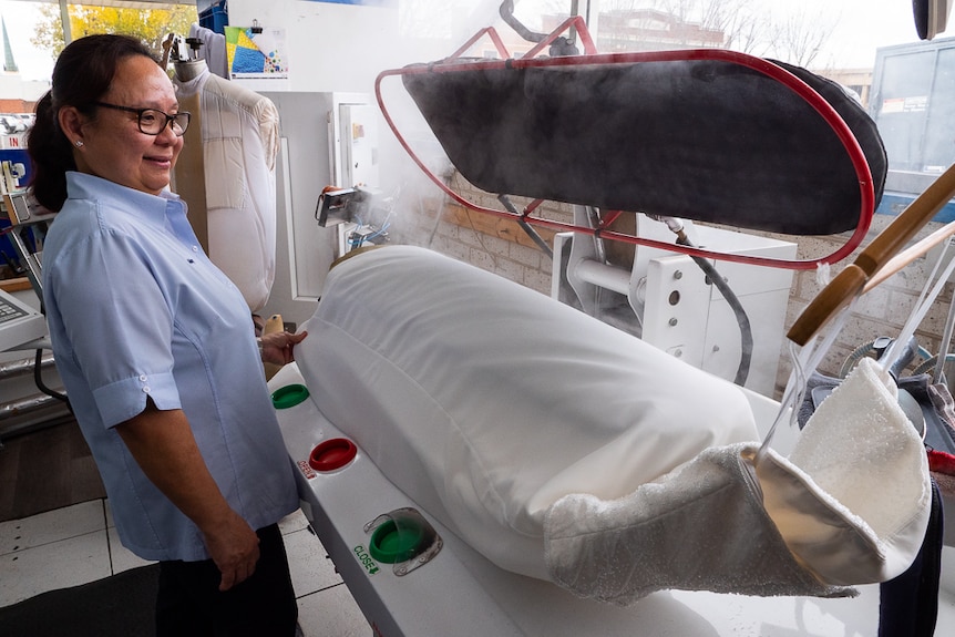 A woman steaming a white wedding dress.