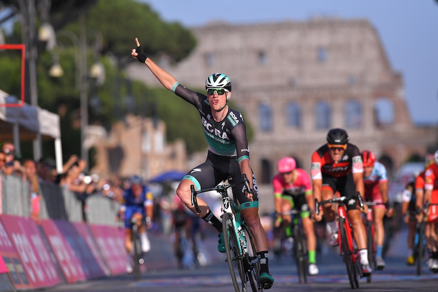 Sam Bennett raises his arm with the Colosseum in the background