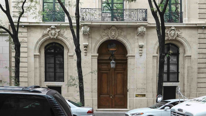 A white stately building with ornate detailing above the doors and windows.