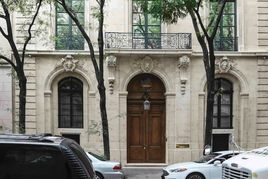 A white stately building with ornate detailing above the doors and windows.