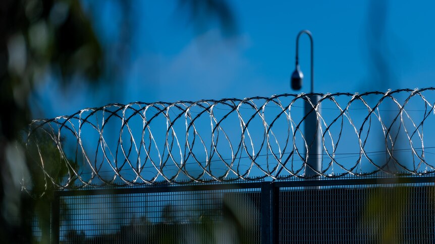 A barbed wire fence with a security camera in the background