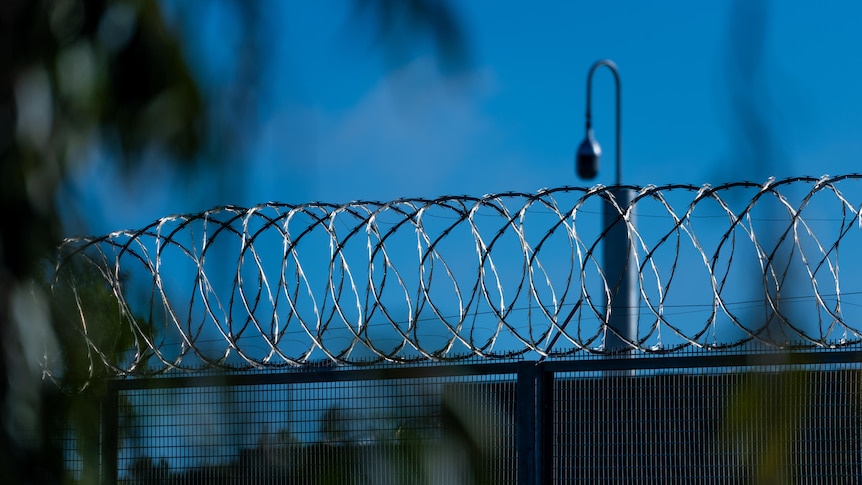 A barbed wire fence with a security camera in the background
