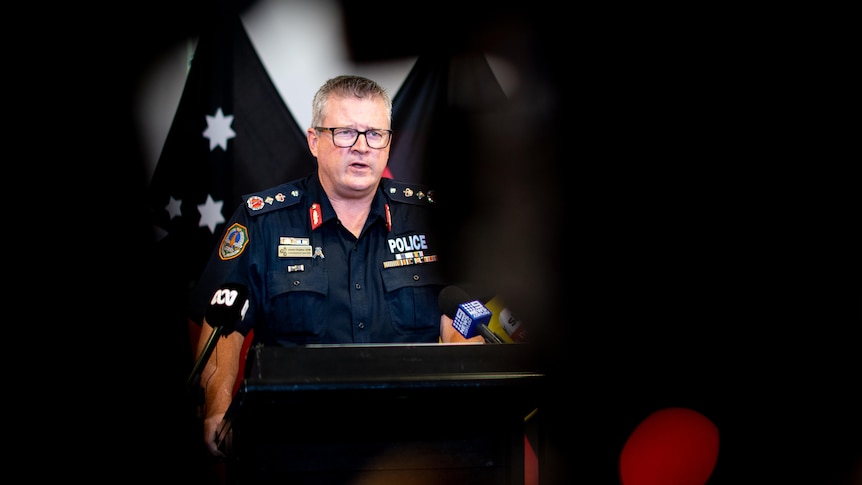 A police officer speaks at a media conference. He looks serious.