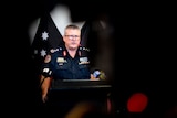 A police officer speaks at a media conference. He looks serious.