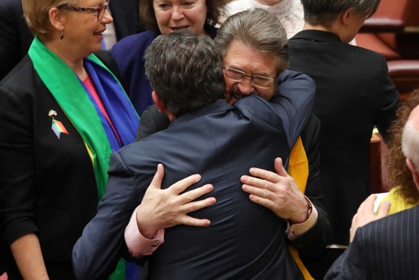 Senators Derryn Hinch and Dean Smith hug after the senate passes the same-sex marriage bill.