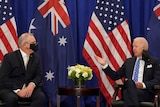 Scott Morrison and Joe Biden sit talking in front of US and Australian flags.