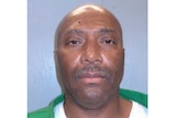 a mugshot of Richard Moore who is wearing a green pullover over a white shirt against a blue background