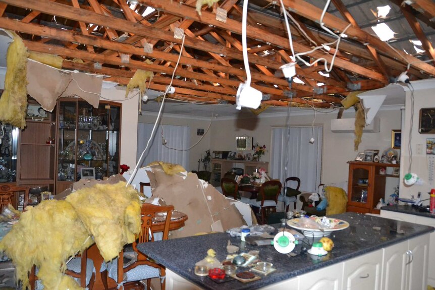 A roof with holes in it and storm wreckage in a kitchen.