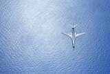 An overhead view of a B-1B Lancer bomber flying over the sea.