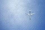 An overhead view of a B-1B Lancer bomber flying over the sea.